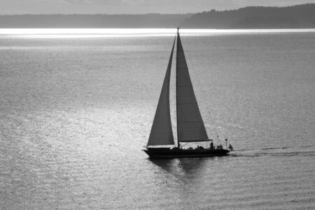 A sailboat in the bay during sunset black and whiteの写真素材