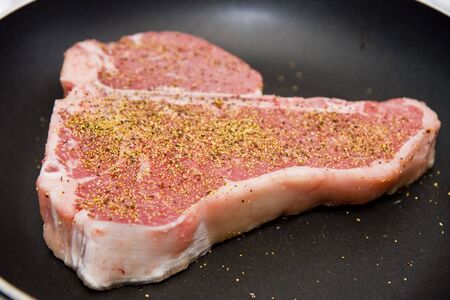 A seasoned porterhouse steak in a skilletの写真素材