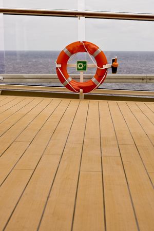 Wooden planks leading to an orange life ring on a shipの写真素材