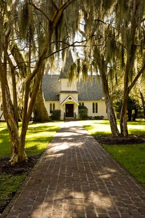 A small old church on a brick walk under oak trees and spanish mossの写真素材