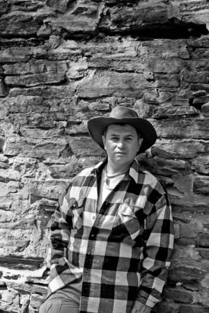 A nice looking hispanic gay man outside by an old rock wall black and whiteの写真素材