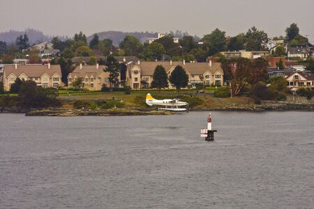A sea plane cruising in to land by houses on the landの写真素材