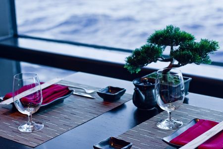 A formal place setting in an Asian restaurant featuring bonsai trees and chopsticksの写真素材
