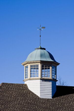 A weather van on an old fashioned cupola on a roofの写真素材