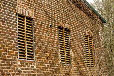 An old brick mill building with wooden slat windowsの写真素材