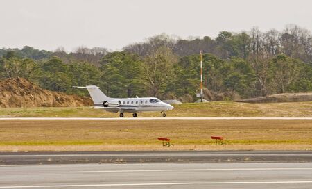A small private jet landing on a small runwayの写真素材