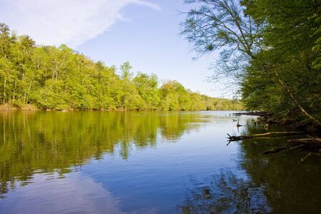 A calm blue river running through a forest of greenの写真素材