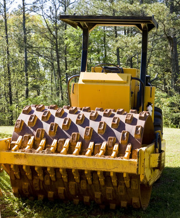 Road paving equipment in a field by a job site