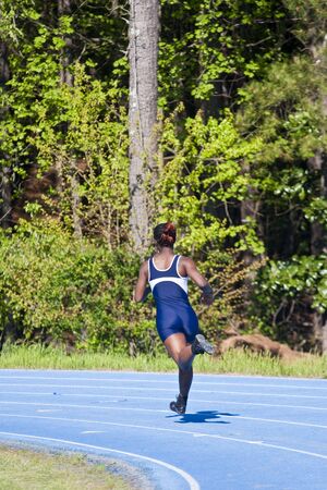 A young woman entering the curve on a track during a raceの写真素材