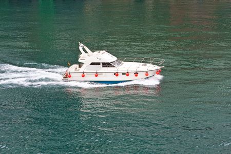 A nice white boat cruising across the blue green waterの写真素材
