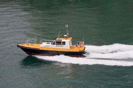A Yellow and Black Pilot Boat speeding through a calm harborの写真素材