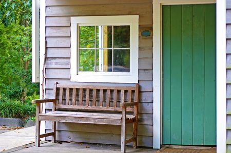 An old wooden bench on the porch of a small cabinの写真素材