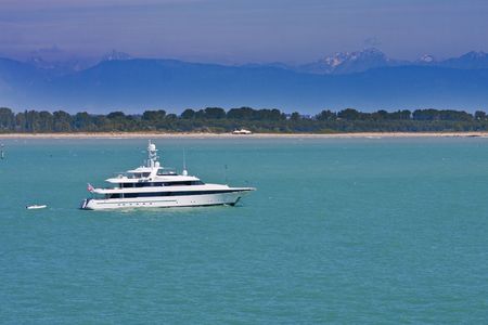 A nice white boat cruising across the blue green water with mountains in the distanceの写真素材