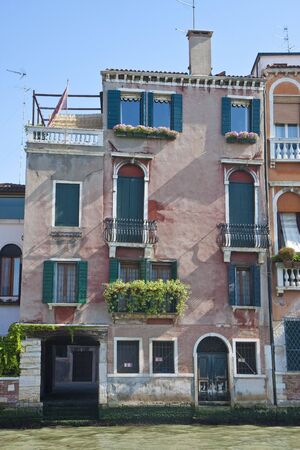 Old pink stucco building on a canal in Venice, Italy against blue skyの写真素材