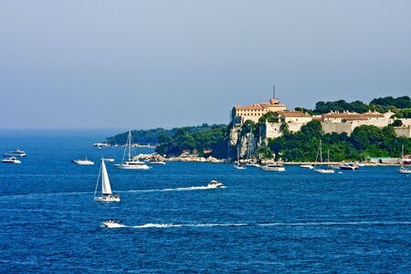 An old French fortress on an island off the coast of Cannes iwth pleasure boats in the blue water of the Mediterraneanの写真素材