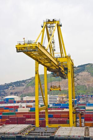 Freight ready for shipping by a loading crane on a hilly coastの写真素材
