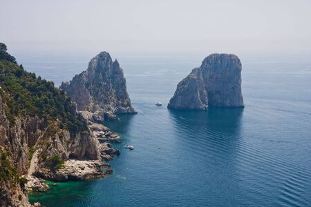 Rocks off the coast of Capri in the Bay of Naples with boats in the waterの写真素材