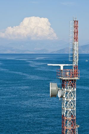 A modern microwave transmission tower against a blue sea and cloudy skiesの写真素材