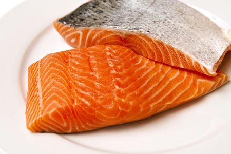 Fresh salmon fillets with skin on a white plateの写真素材