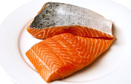 Fresh salmon fillets with skin on a white plateの写真素材