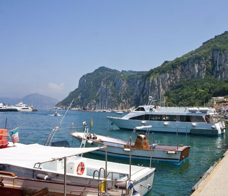 A pier with colorful boats by the rocky cliffs of Capriの写真素材