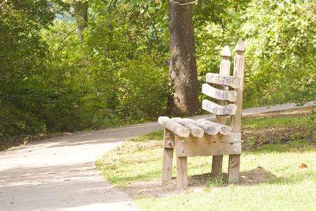 An old rustic wooden bench on a paved walking trail in the parkの写真素材