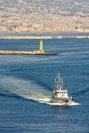 A military vessel moving across the blue water in a harborの写真素材