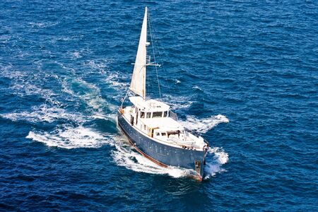 A large motor boat with a sail attachedの写真素材