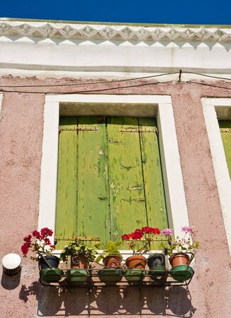 An old green wood window with flowers in a basketの写真素材