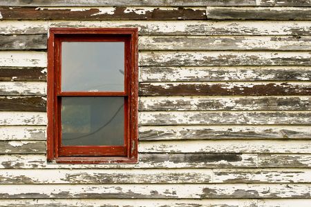 An old building with peeling paint and a red windowの写真素材