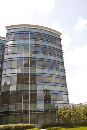 A modern glass office building reflecting other buildingsの写真素材