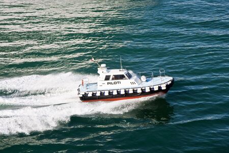 An Italian pilot boat speeding across a calm blue bayの写真素材