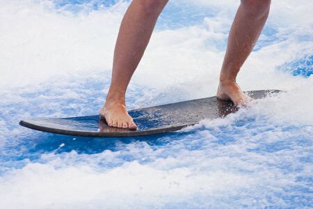 A surfer riding a short boar in a wave poolの写真素材