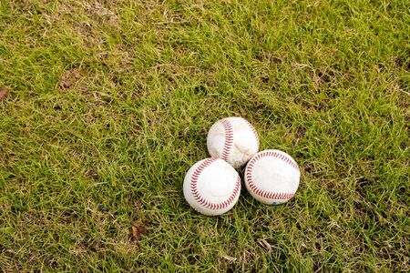 Three baseballs on the green grass of a fieldの写真素材