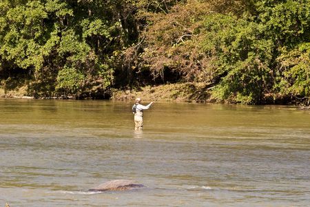 A fly fisherman casting his line in a muddy riverの写真素材