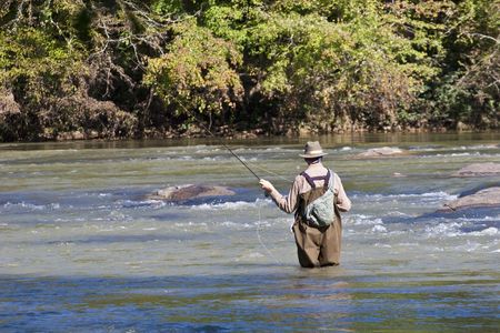 A fly fisherman casting a line in the riverの写真素材