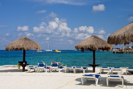 A couple lougning in beach chairs under straw umbrellasの写真素材