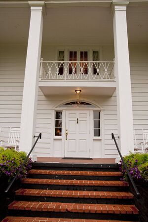 Brick steps leading up to the front door of a white columned wood siding houseの写真素材