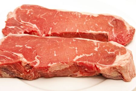Two fresh prime strip steaks on a white plateの写真素材