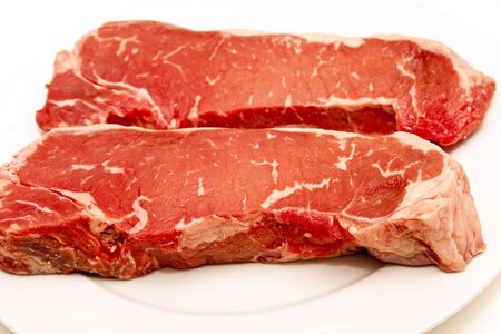 Two fresh red strip steaks on a white plateの写真素材