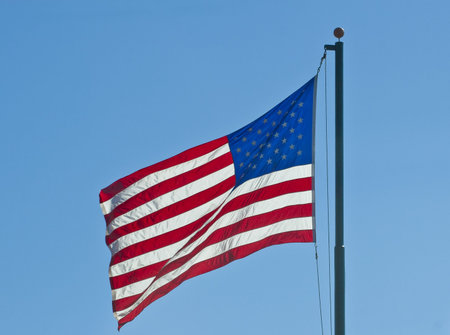 An American flag blowing in the wind on a blue sky