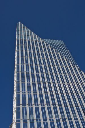 A modern blue and silver office tower rising into a blue skyの写真素材