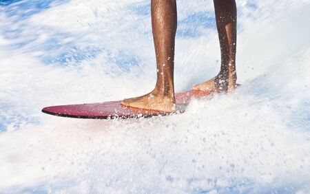 A black man on a red surfboard in blue and white surfの写真素材