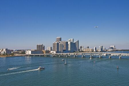 A jet flying over Miami with boats cruising into Biscayne Bayの写真素材