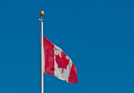 A Canadian flag flying against a blue skyの写真素材
