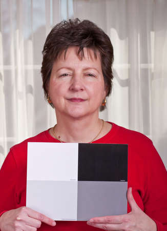 A woman holding up a white and grey card for a photographerの写真素材