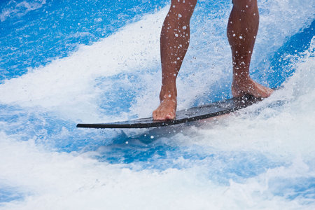 A surfer on a black board on blue water