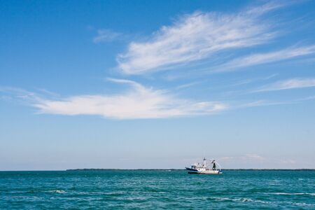 A shrimp boat under high white cloudsの写真素材