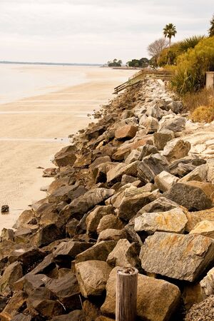 A rocky seawall on a beach on a cloudy dayの写真素材