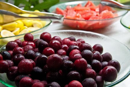 Fresh purple plums in a glass bowl on a fruit buffetの写真素材